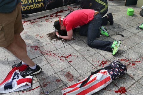 A man comforts a woman on the sidewalk at the scene of the first explosion near the finish line of the 117th Boston Marathon, April 15, 2013.
