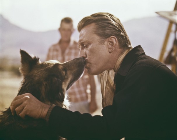 American actor Kirk Douglas kissing a German shepherd, circa 1962. 