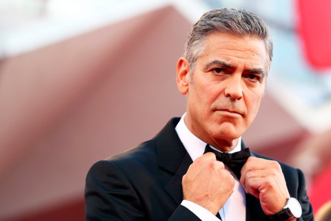 U.S. actor Clooney adjusts his bowtie as he arrives on the red carpet for the premiere of "Gravity" at the 70th Venice Film Festival