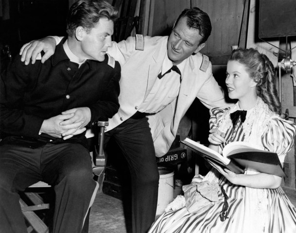 John Wayne (center) talks with John George Agar (left) and Shirley Temple (right) on the set of the film Fort Apache in 1948.